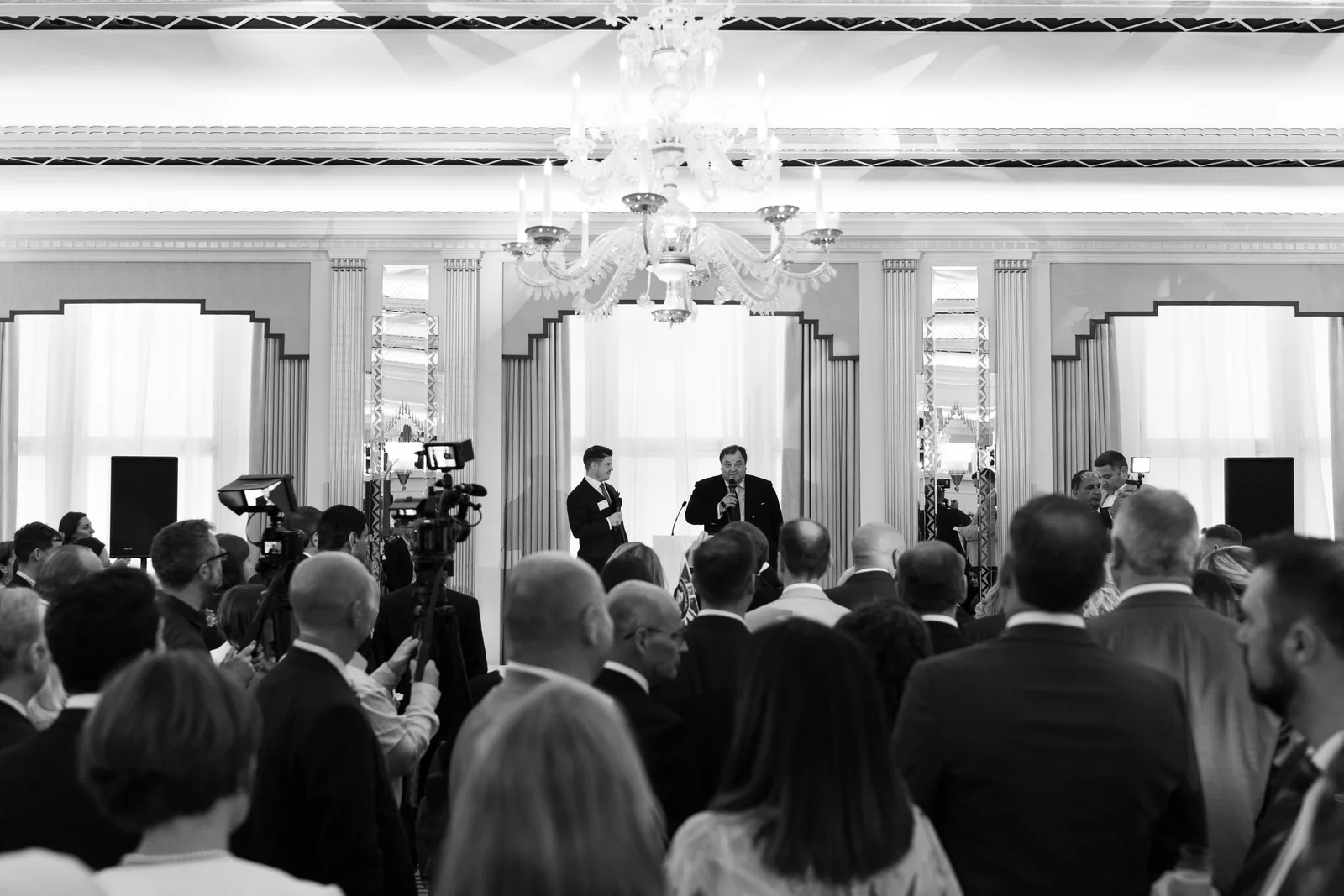 An audience listening to a presentation, in black and white